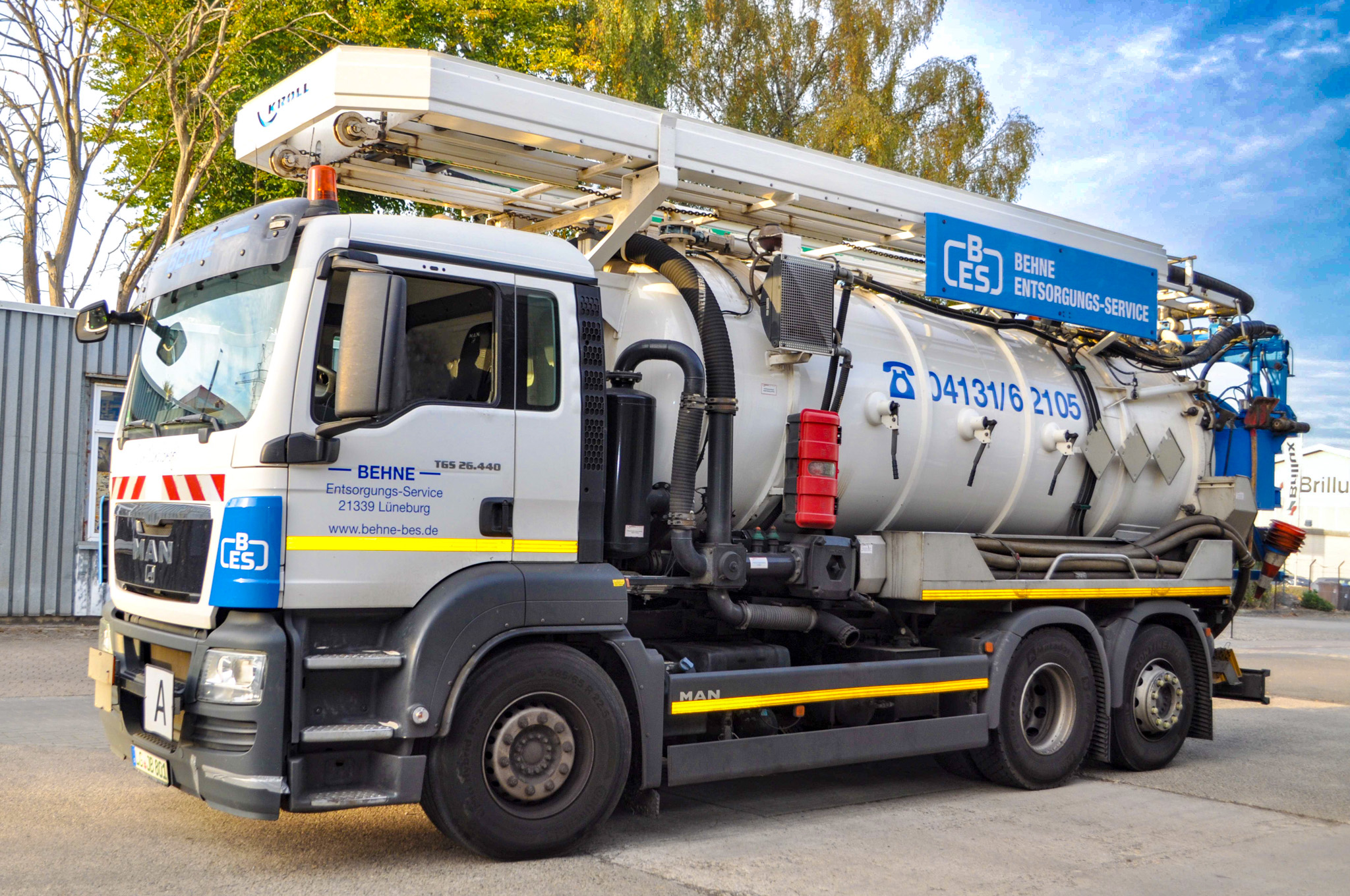 Saugwagen der Behne Entsorgungs-Service GmbH, MAN TGS 26.440, dreiachsiges Tankfahrzeug mit silbernem Edelstahltank und blau-weißer Fahrzeugbeschriftung, Standort Lüneburg